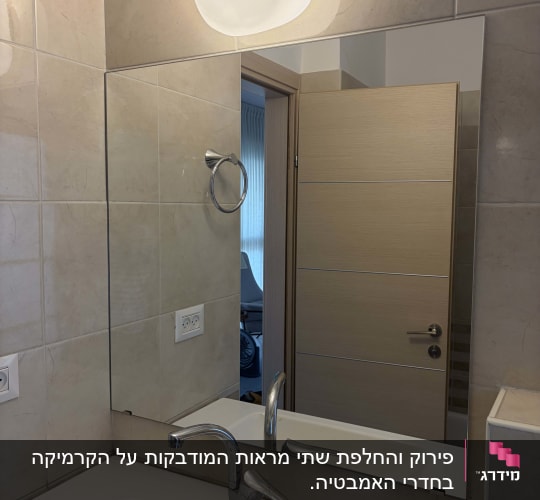 מראה מלבנית גדולה מותקנת על קיר קרמיקה מעל כיור בחדר רחצה